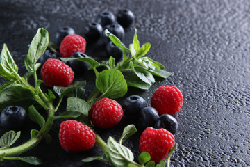 Fresh berries: blueberries, raspberries and fresh mint on a black background. Background image, copy space