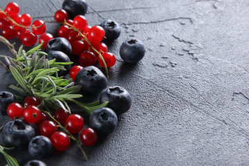 Fresh berries: blueberries, red currants and herbs on a dark grey background. Background image, copy space