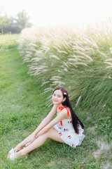 Beautiful Asian woman wear white dress siting on lawn in garden.