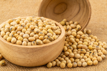 Soy beans in a wooden bowl with a  pile of soy beans on sackcloth