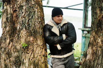 Serious man arabian on leather jacket and black hat copies his idol from action movie.