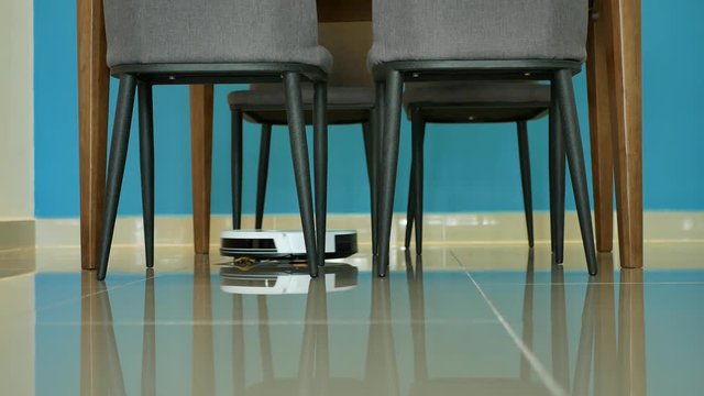 Robotic vacuum cleaner cleaning the floor in dining area.