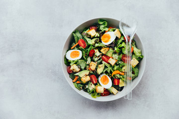 Healthy salad bowl with eggs, avocado and tomatoes sprinkled with sunflower and pumkin seeds.
