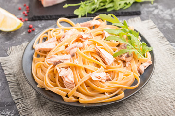 Semolina pasta with salmon and salmon steak on a black concrete background. Side view, selective focus.