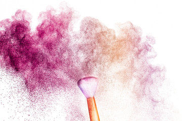 A golden brush with pink and light brown  make up powder impact to make a colorful cloud.
