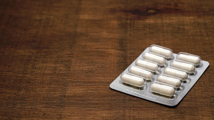 Fototapeta na wymiar Herbal medicine panels are packaged in capsules on a wood grain background.