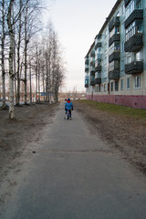 The kid rides alone on a bicycle on an empty spring street of the provincial city. Social distance due to quarantine, coronavirus, pandemic, sepieda.