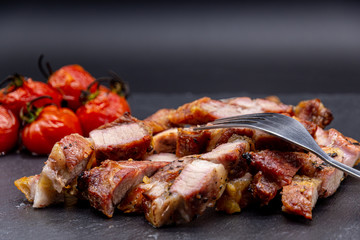 pork steak on black slate and grilled tomatoes ans salt