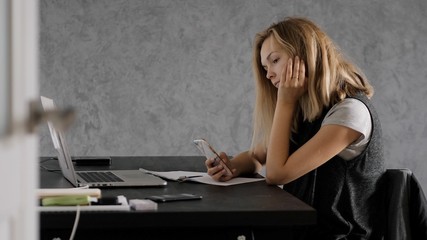 Young woman sitting at a Desk, online learning, laptop, and smartphone