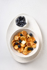 Mini pancakes with blueberry on white background. View from above.