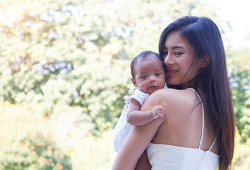 Portrait of young mother holding her newborn daughter smiling. Mom's love.