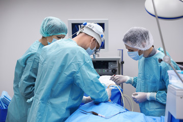 Team of professional doctors performing operation in surgery room
