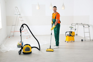 Professional janitor cleaning floor with mop after renovation