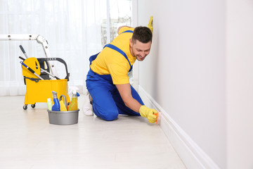 Professional janitor cleaning baseboard with brush after renovation