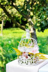 Floral arrangement with roses, alstroemeria and solidago flowers inside a vintage bird cage
