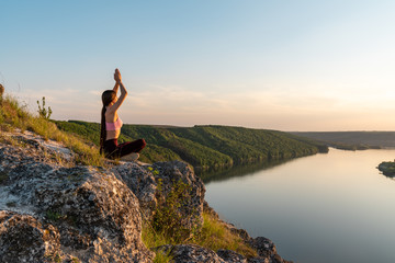 Young girl doing yoga fitness exercise in the morning sunrise outdoor in the meadow beautiful mountains landscape