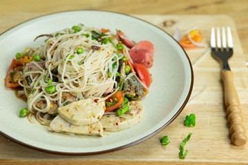 Lightly fermented rice noodles mix spicy on plate have fork near on wood floor top view angle