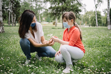 Side-view of mom and child holding fresh bouquet in park. Young daughter giving camomile bouquet to her mother while enjoying good weather in park.