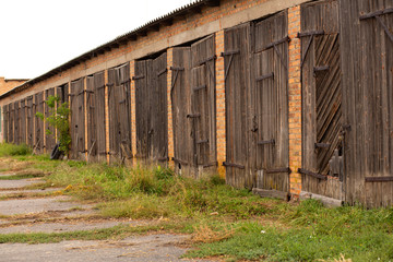 Naklejka premium Old cowshed. Large wooden gate and dried wood. Old brick building