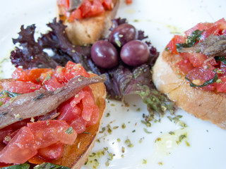 Bruschetta antipasto with tomato and anchovy and olives