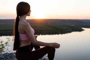 Healthy life exercise concept - Woman practices pranayama yoga breath control in lotus pose padmasana outdoors in the mountains in the morning on sunrise