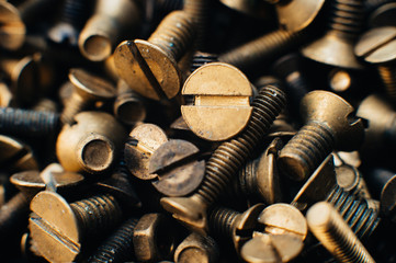 Close-up, macro. Old Soviet brass countersunk head screws with a flat head screwdriver. Texture, background of screws. Gold color screws. Dirty wood screws in oil. Brass scrap metal