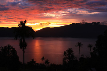 Naklejka na ściany i meble Beautiful sunset with palm trees on Lake Maninjau