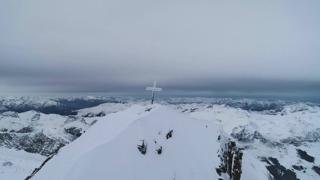 Fly past cross on top of mountain at the top of the Austrian Alps in winter