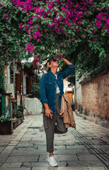 Fototapeta na wymiar Pretty adult woman smelling spring flowers in streets of Antalya’s old town. Old town in city centrum is a must see place for tourists during their visit to Antalya.