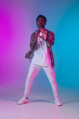 Obraz premium African-american male singer portrait isolated on gradient studio background in neon light. Beautiful male model with microphone. Concept of human emotions, facial expression, ad, music, art.