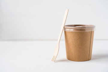 A disposable container and a wooden fork. Food delivery concept.