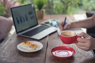 business man working with his laptop computer and drinking coffee on wooden desk at coffee shop 