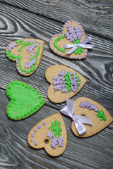 Gingerbread cookies decorated with glaze. Made in the shape of a heart. On some ribbons tied to a bow. On brushed pine boards.