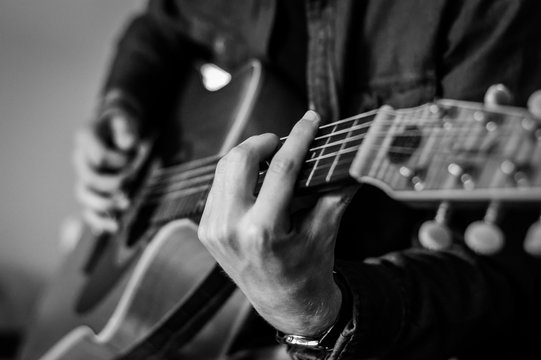 Guitar player chords close up on the strings - black and white, selective focus.