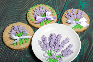 Obraz na płótnie Canvas Gingerbread cookies decorated with glaze. Some are decorated with a ribbon tied to a bow. Near a saucer with a pattern of glaze. On brushed pine boards.