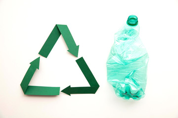 Green paper recycling symbol with empty plastic water bottles