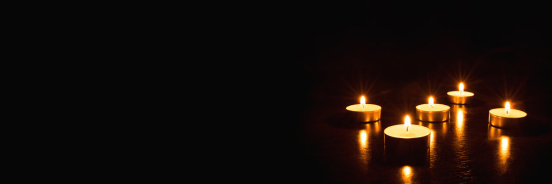 Several burning candles on a black background. Banner with copy space.