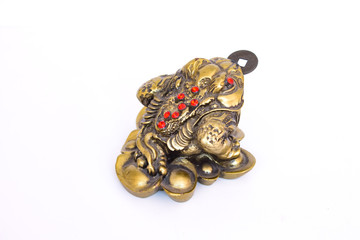 a bronze money toad with a coin in his mouth sits on a white background. Kind of a shady