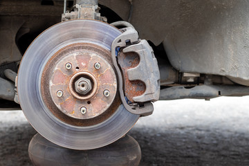 Rusty back car wheel hub with brake disc at tire shop. Car without a wheel while replacing on the...