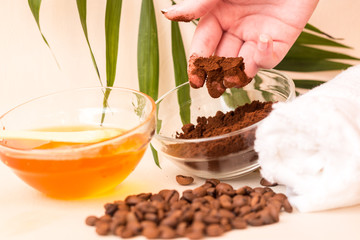 Spa care at home. A woman's hand holds ground coffee. Scrub of coffee and honey. Bright background. Space for text. Horizontal photo. The view from the top.