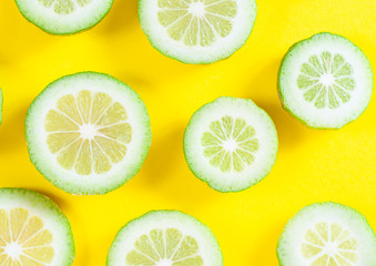 Green lime slices on yellow background