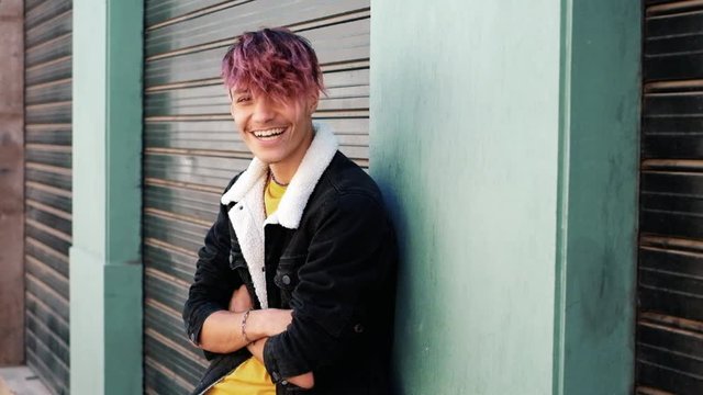 Urban style generation z young teenager portrait with city wall in bakground - alternative and diversity people concept with handsome coloured hair male - youth lifestyle