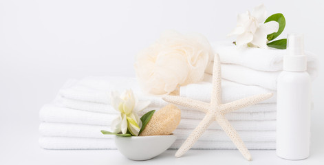 Fototapeta na wymiar Spa and health care concepts setup with stack of white towels star fish,Gardenia flowers,spray bottle,and loofah scrub on white background