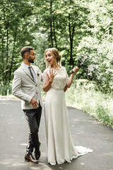 Lovely newlyweds hugging and smiling in a green park. Portrait of the bride and groom in a lace dress. Wedding day of a happy newlywed couple