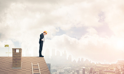 Engineer man standing on roof and looking down. Mixed media