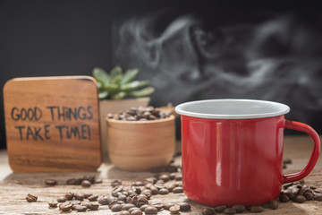 Steam coffee red cup with text,roasted beans and flower pot on wood background in morning sunlight