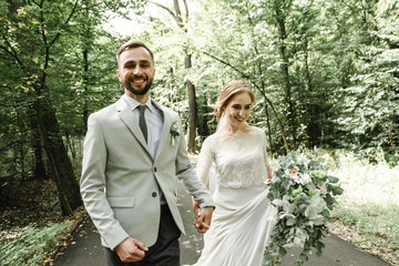 Just married couple dancing valse outdoors, free space. Bride and groom hug, blurred green grass...