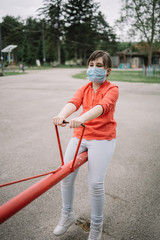 Young girl with antivirus mask enjoying playground facilities. Portrait of child with antivirus mask having fun at playground during covid-19 pandemic.