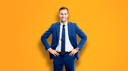Fototapeta na wymiar Happy smiling businessman in hands on hips pose, standing over orange color background. Portrait of handsome male caucasian model at studio picture. Copy space for some text or slogan.