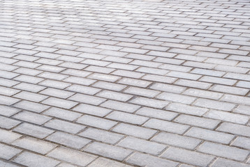 Texture of gray patterned paving tiles on the ground of street, perspective view. Concrete paving slab flagstone. Cement brick squared stone floor background. Sidewalk pavement pattern.